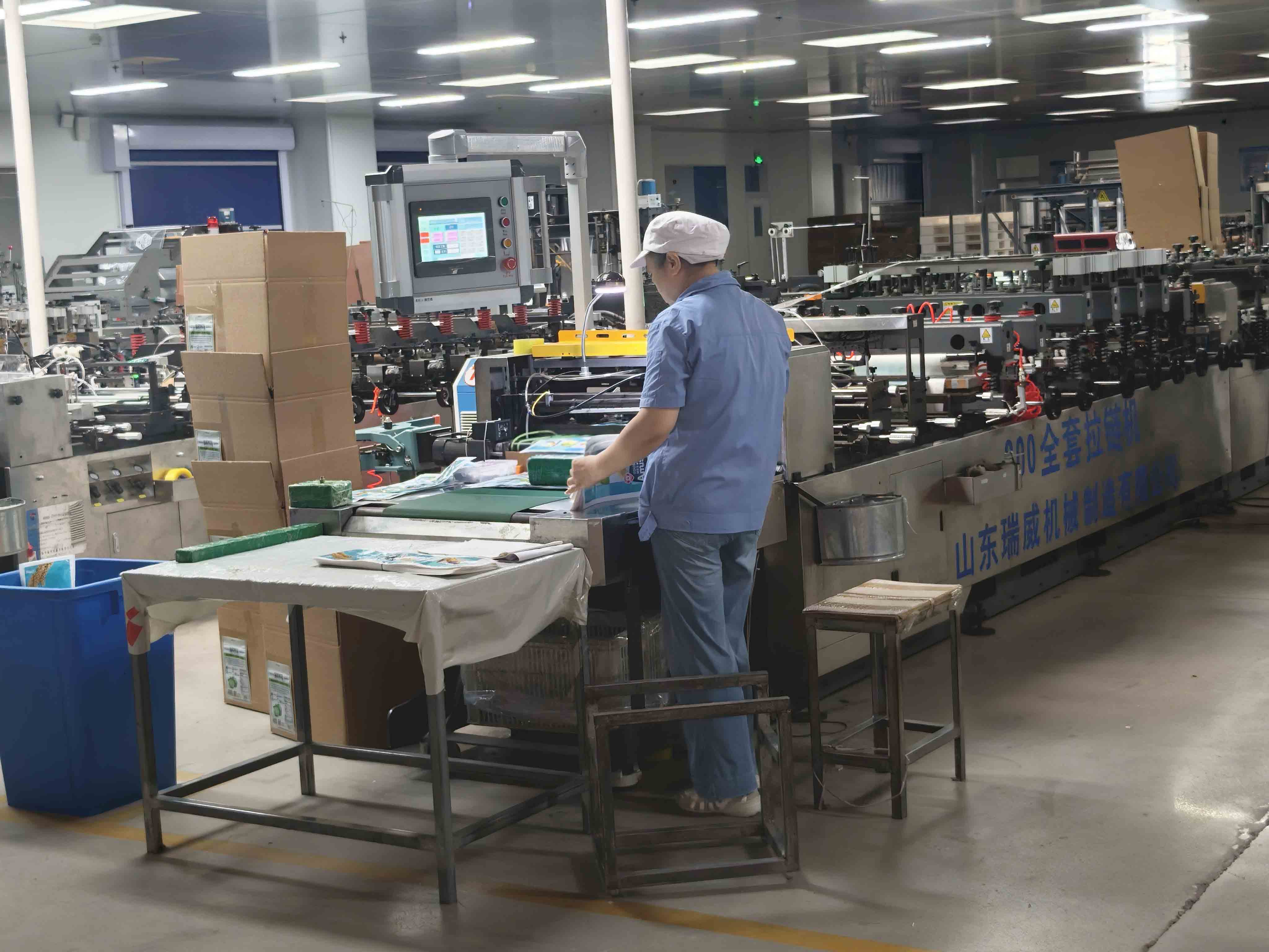 An operator working beside pouch-making equipment and a packing table