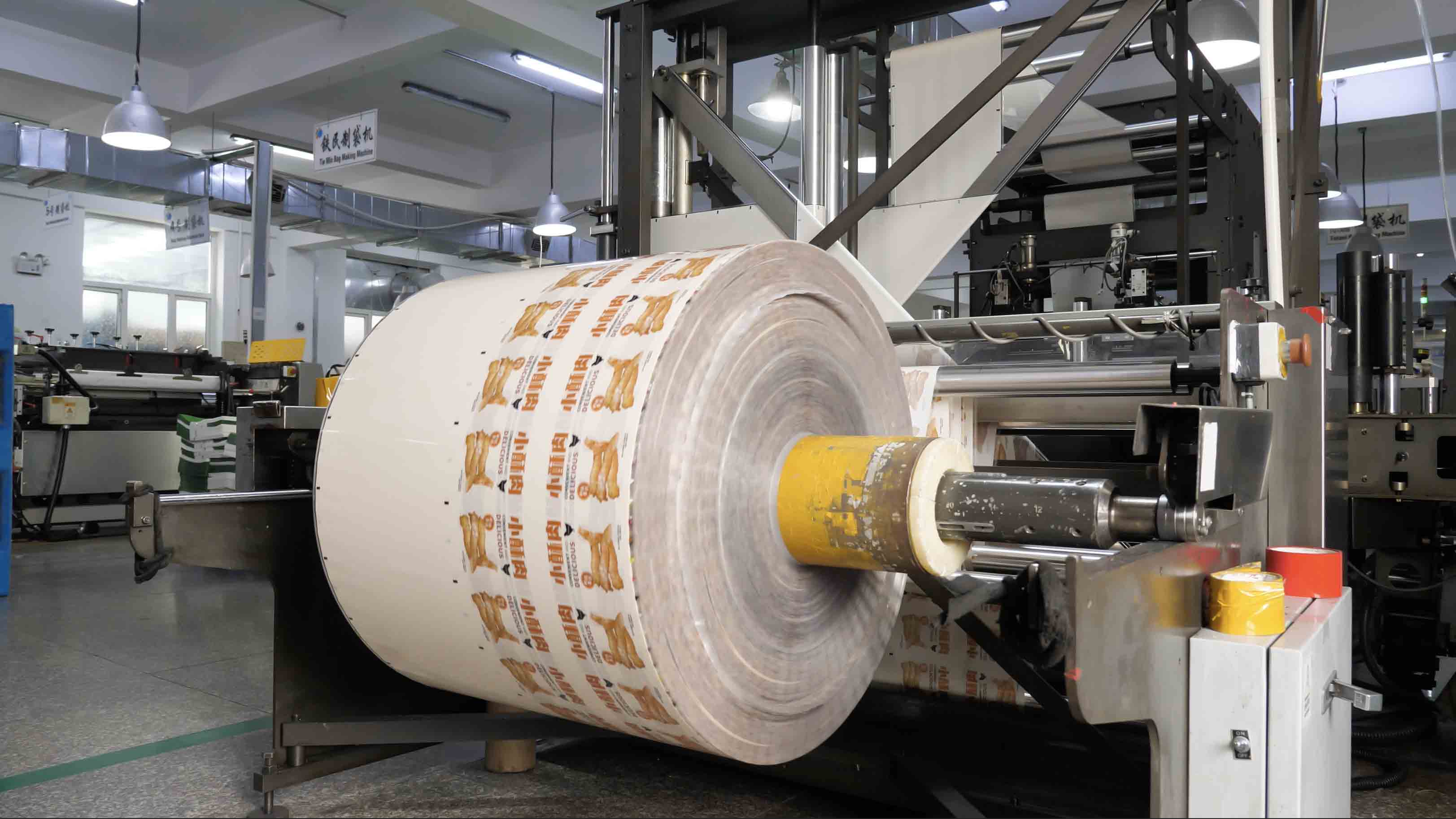 A roll of printed flexible packaging film on converting equipment